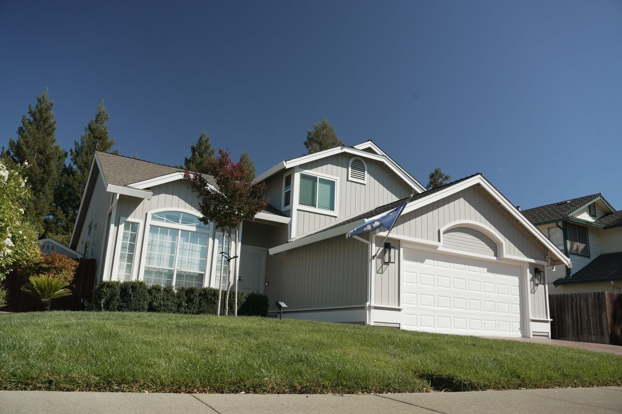 Completed exterior of a two-story home with light siding and contrasting white trim.