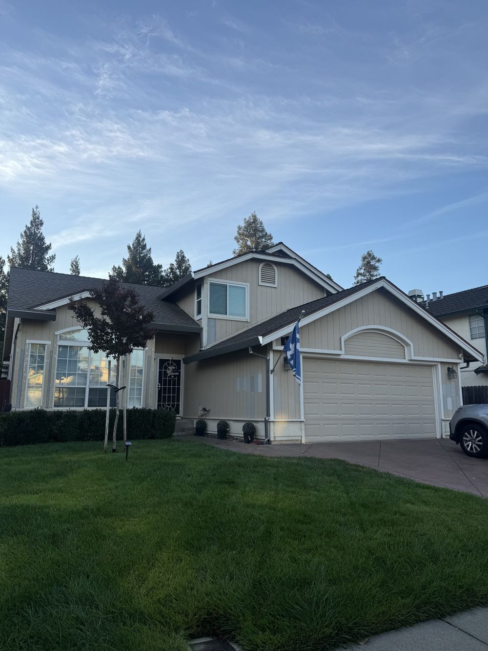 Front of the two-story home before painting, showing siding, trim and garage.