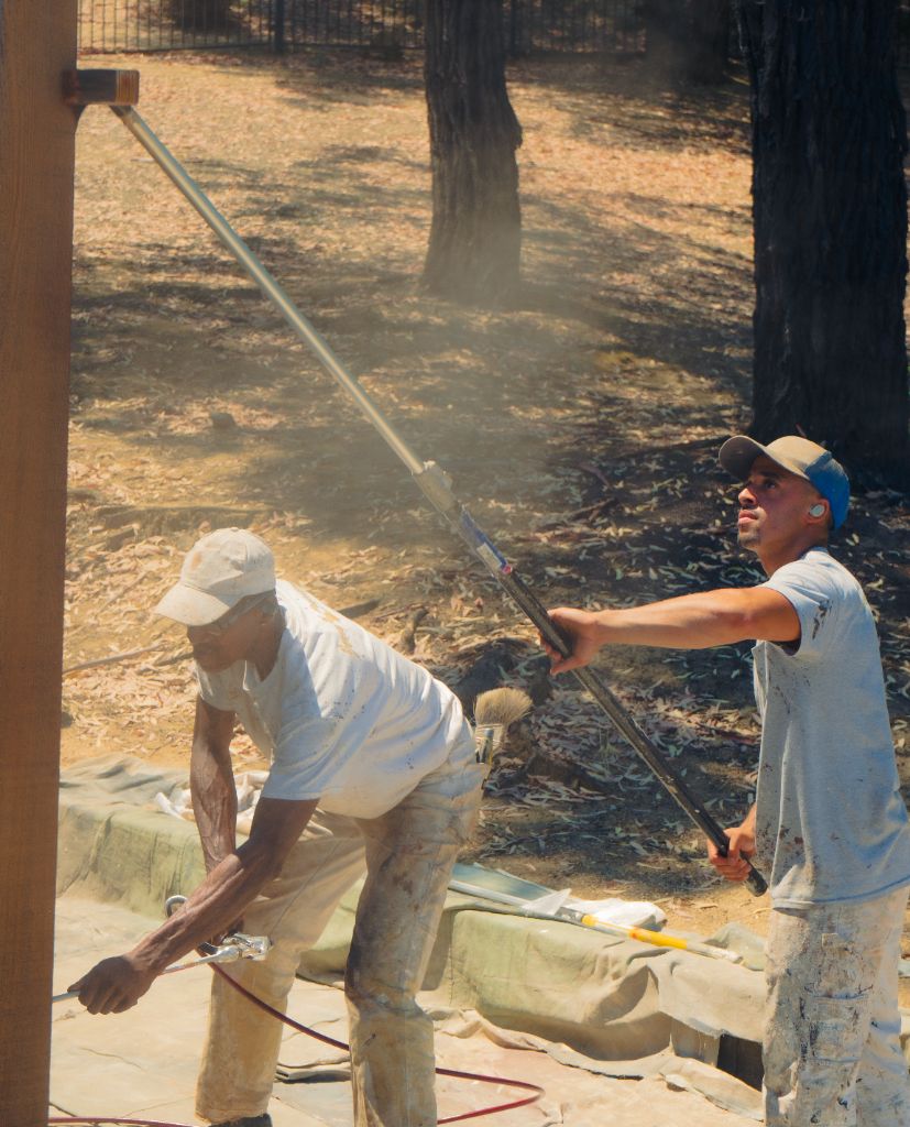 Milestone Painting crew applying stain to wood siding