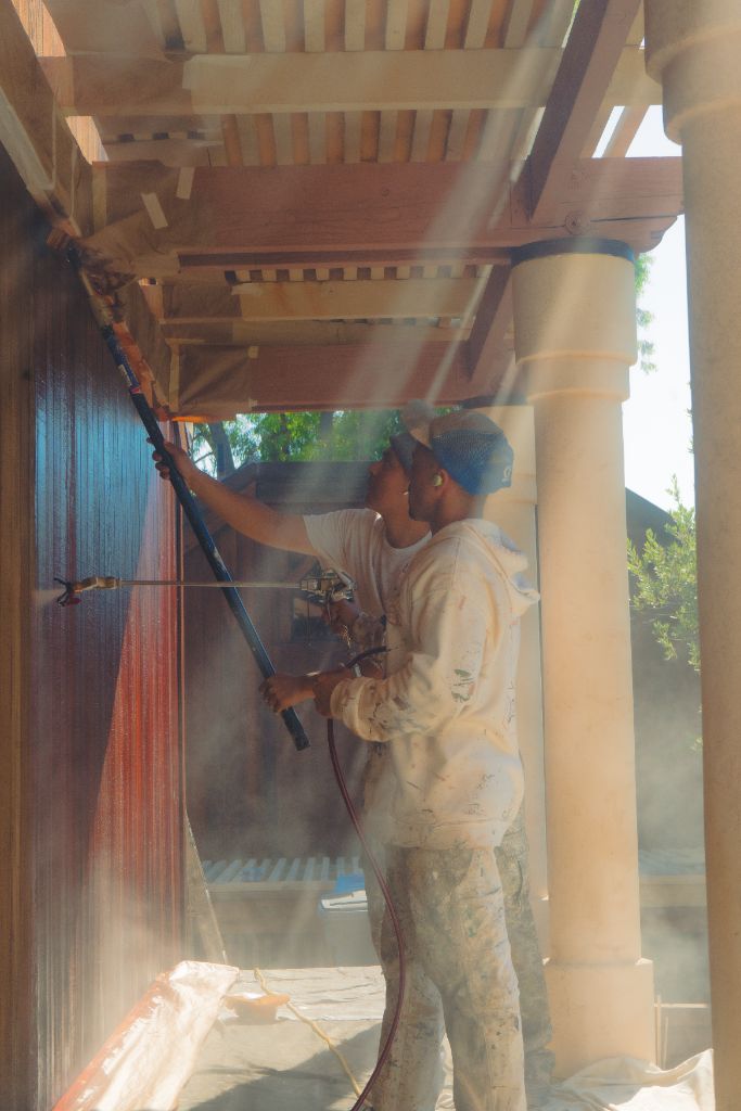 Two painters on roof applying stain to wood siding — Milestone Painting NorCal estate