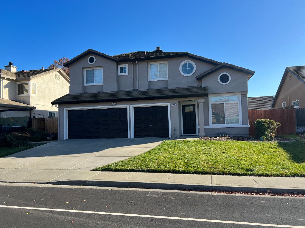 Two-story home exterior repainted in warm tan — Milestone Painting