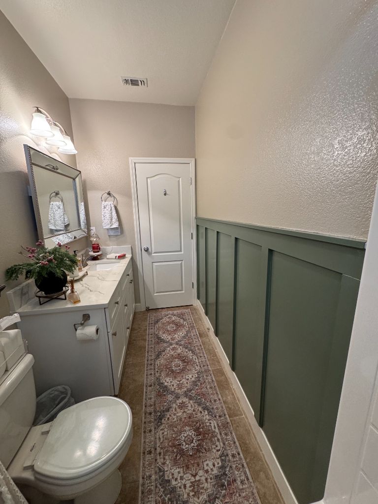 Freshly painted bathroom with sage green board and batten accent wall